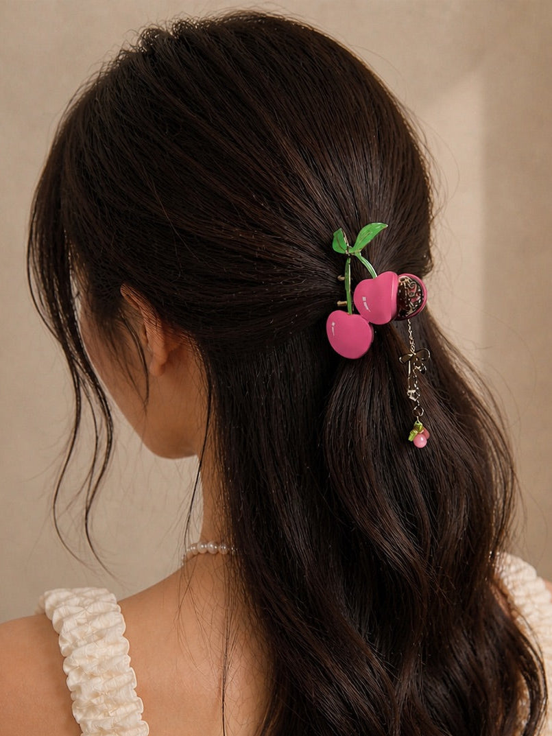 Woman with long dark hair wearing a cherry mauve claw clip with charm accessory standing against a beige background